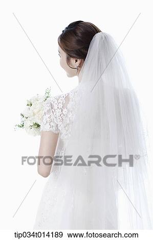 Stock Photo - back shot of a woman in wedding dress holding flower bouquet. Fotosearch