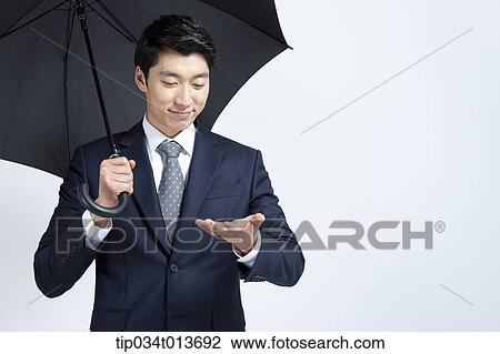 Stock Image - businessman with black umbrella holding something in the hand. Fotosearch