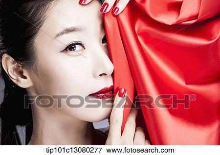 Stock Photo - close up shot of a woman covering her face with red curtain. Fotosearch