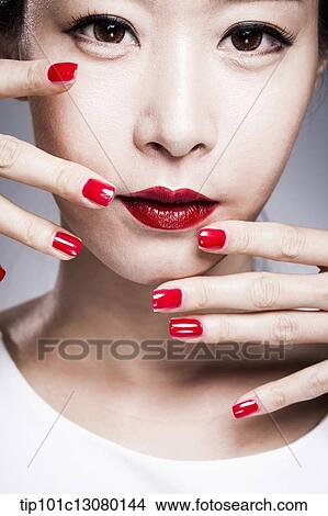 Picture - close up shot of a woman in red lipsticks and red nails. Fotosearch