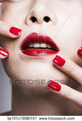 Stock Image - close up shot of a woman in red lipsticks and red nails. Fotosearch