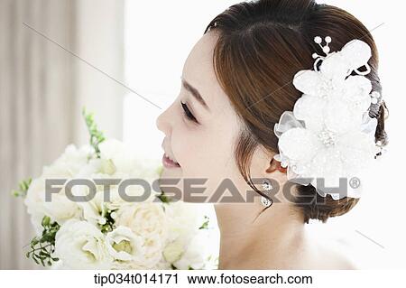 Stock Image - close up shot of a woman in wedding hair holding flower. Fotosearch