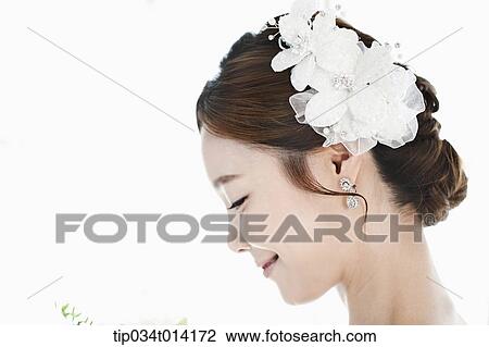 Stock Image - close up shot of a woman in wedding hair holding flower. Fotosearch