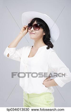 Stock Image - close up shot of a woman in white hat and sunglasses. Fotosearch
