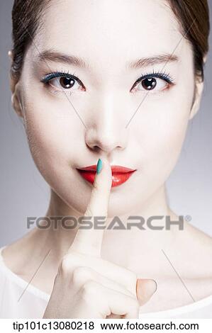 Stock Photo - close up shot of a woman with a finger in her red lips. Fotosearch