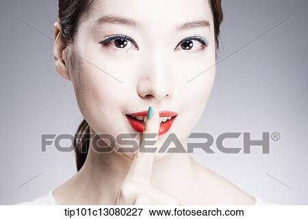 Stock Photo - close up shot of a woman with a finger in her red lips. Fotosearch
