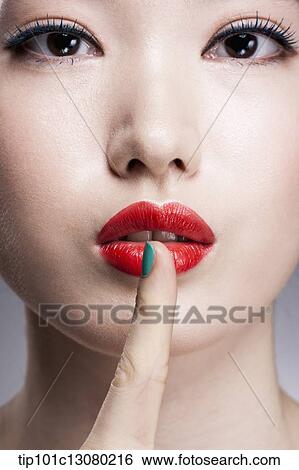 Stock Photograph - close up shot of a woman with a finger in her red lips. Fotosearch