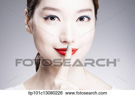 Stock Photograph - close up shot of a woman with a finger in her red lips. Fotosearch