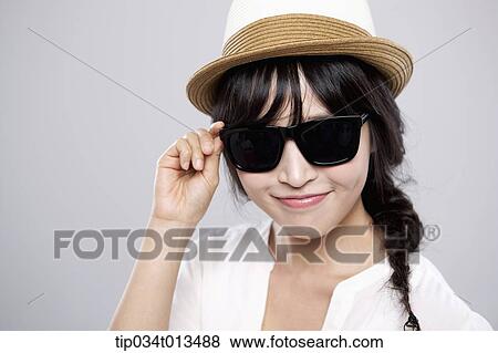 Stock Photo - close up shot of a woman with a hat posing with sunglasses. Fotosearch