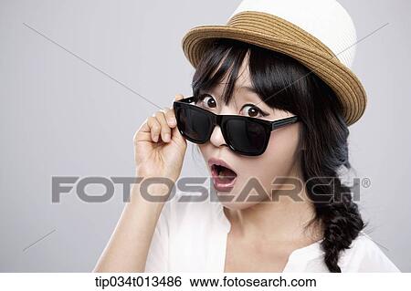 Stock Photograph - close up shot of a woman with a hat posing with sunglasses. Fotosearch