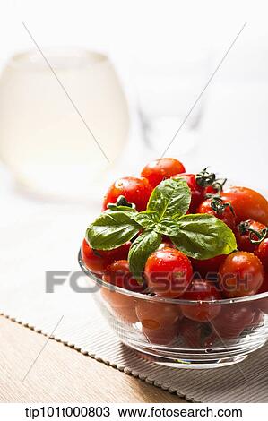 Stock Image - close up shot of sweet pea tomatoes in a glass bowl. Fotosearch