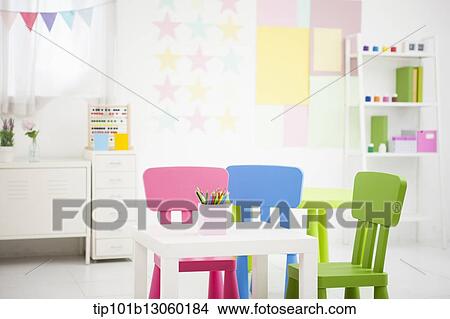Picture - different color kids chairs in a room. Fotosearch