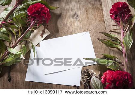 Stock Photo - envelops and red flowers on wooden surface. Fotosearch