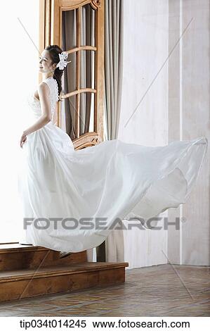 Stock Photography - full shot of a woman in wedding dress stepping up the stairs. Fotosearch