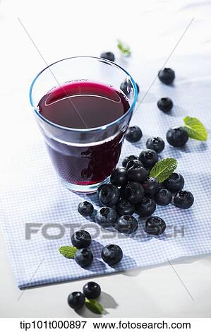 Stock Photo - glass of berry juice with blue berries . Fotosearch