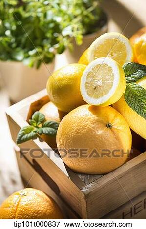 Stock Photo - grape fruits in a box next to vases of plants. Fotosearch