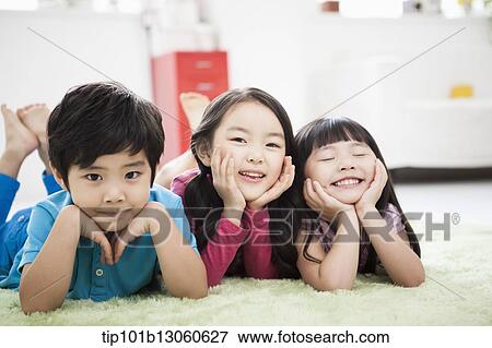 Stock Photo - kids lying in the floor carpet with hands under their chin. Fotosearch