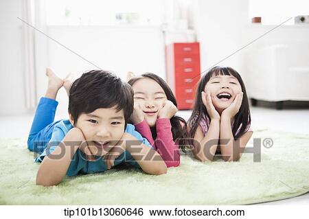 Stock Photograph - kids lying in the floor carpet with hands under their chin. Fotosearch