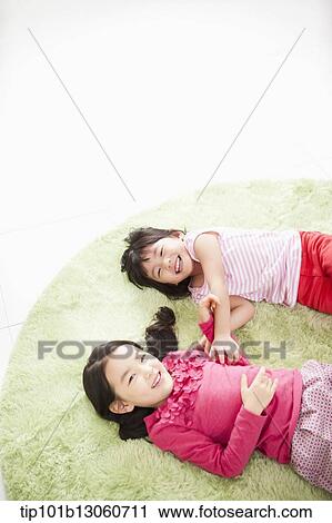 Stock Image - kids lying on a carpet playing. Fotosearch
