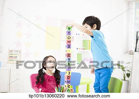 Stock Image - kids playing piling up toy cubes on a table. Fotosearch