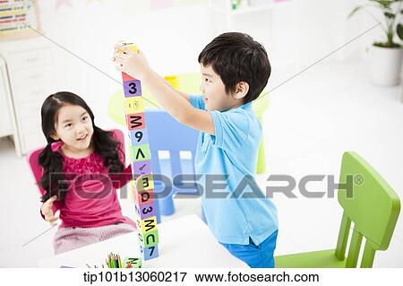 Stock Photo - kids playing piling up toy cubes on a table. Fotosearch