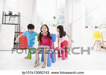 Stock Image - kids playing with different color chairs. Fotosearch