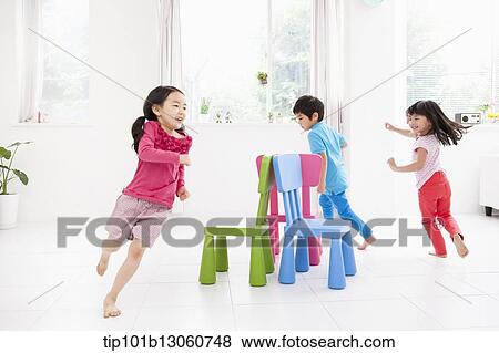 Stock Photo - kids playing with different color chairs. Fotosearch