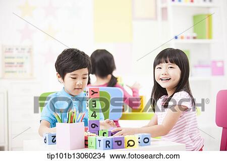 Picture - kids playing with toy cubes on a table. Fotosearch