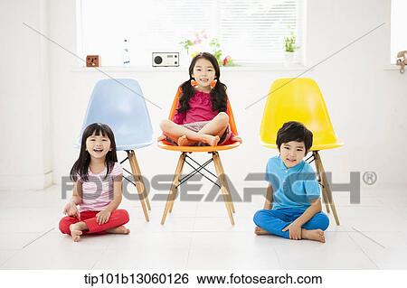 Stock Photograph - kids sitting next to chairs. Fotosearch