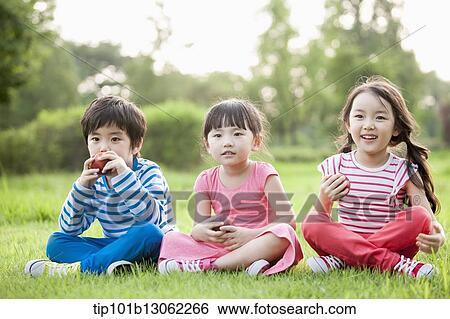 kids sitting on the grass eating apples View Large Photo Image Stock Photograph - kids sitting on the grass eating apples. Fotosearch