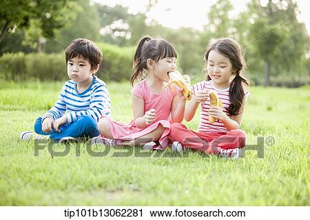 kids sitting on the grass eating bananas View Large Photo Image Stock Image - kids sitting on the grass eating bananas. Fotosearch