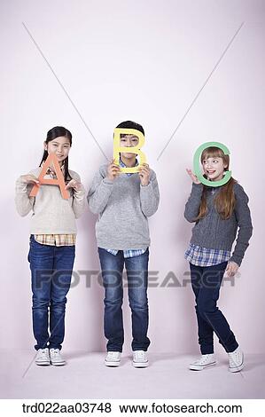 Stock Photo - kids standing and holding alphabets. Fotosearch