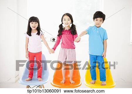 Stock Image - kids standing on chairs. Fotosearch