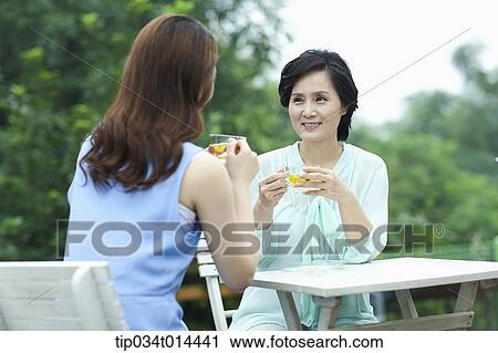 Stock Image - mother and grown up daughter having cup of tea. Fotosearch