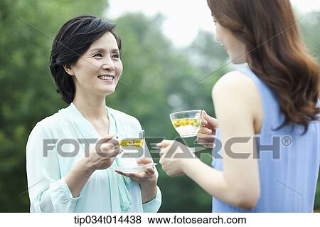 Stock Photo - mother and grown up daughter having cup of tea. Fotosearch