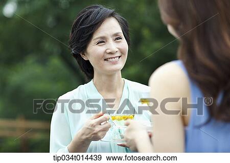 Stock Photo - mother and grown up daughter having cup of tea. Fotosearch