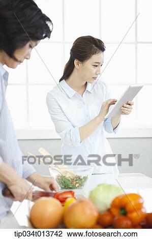 one woman cutting vegetables while the other woman uses tablet PC View Large Photo Image Stock Image - one woman cutting vegetables while the other woman uses tablet PC. Fotosearch