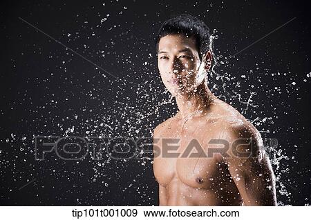 Stock Photo - side shot of a fit man in black background with water splash. Fotosearch