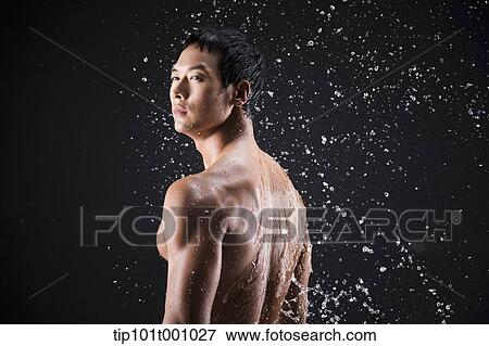 Stock Photo - side shot of a fit man in black background with water splash. Fotosearch