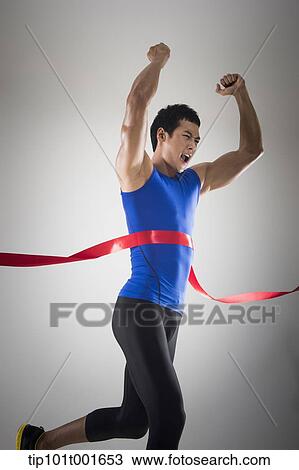 Stock Image - side shot of a fit man in blue shirt running to a finishing line. Fotosearch