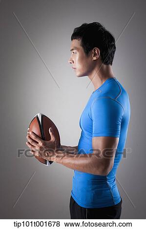 side shot of a fit man in blue shirt posing with rugby ball View Large Photo Image Stock Photo - side shot of a fit man in blue shirt posing with rugby ball. Fotosearch