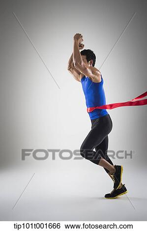 Stock Photograph - side shot of a fit man in blue shirt running to a finishing line. Fotosearch