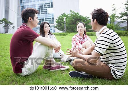 Stock Image - students sitting on grass having a conversation. Fotosearch