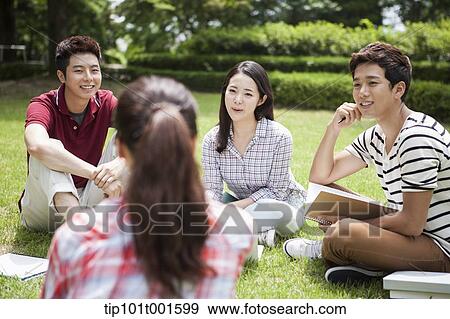 Stock Photo - students sitting on grass studying together. Fotosearch