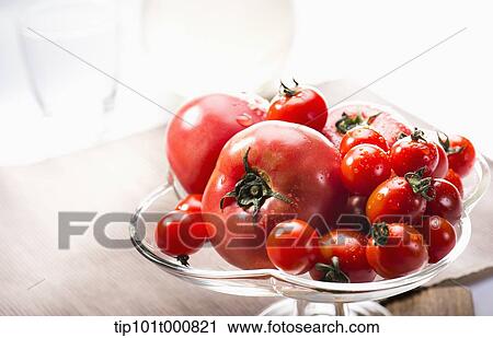 Stock Image - tomatoes on a glass fruit plate . Fotosearch