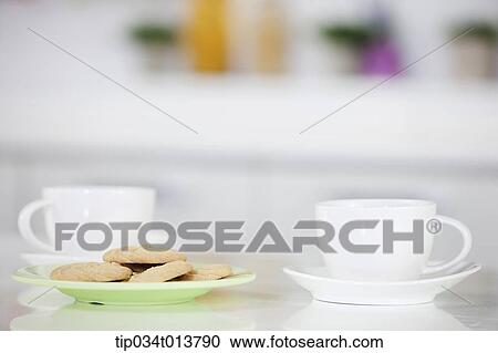 Stock Image - two cups of coffee and a plate of cookies in the kitchen. Fotosearch