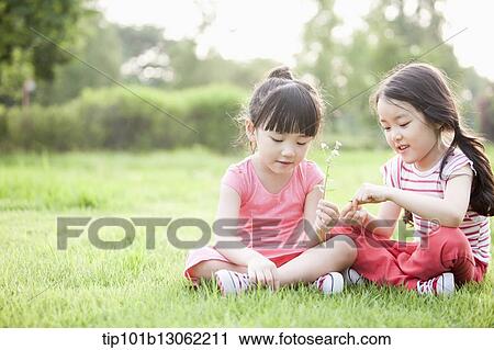 Stock Image - two girl sitting on the grass. Fotosearch