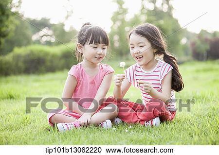 Stock Image - two girl sitting on the grass. Fotosearch