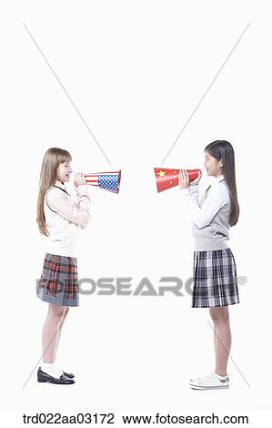 Stock Image - two girls dressed as students with paper megaphones. Fotosearch