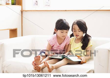 Stock Image - two girls reading a book. Fotosearch